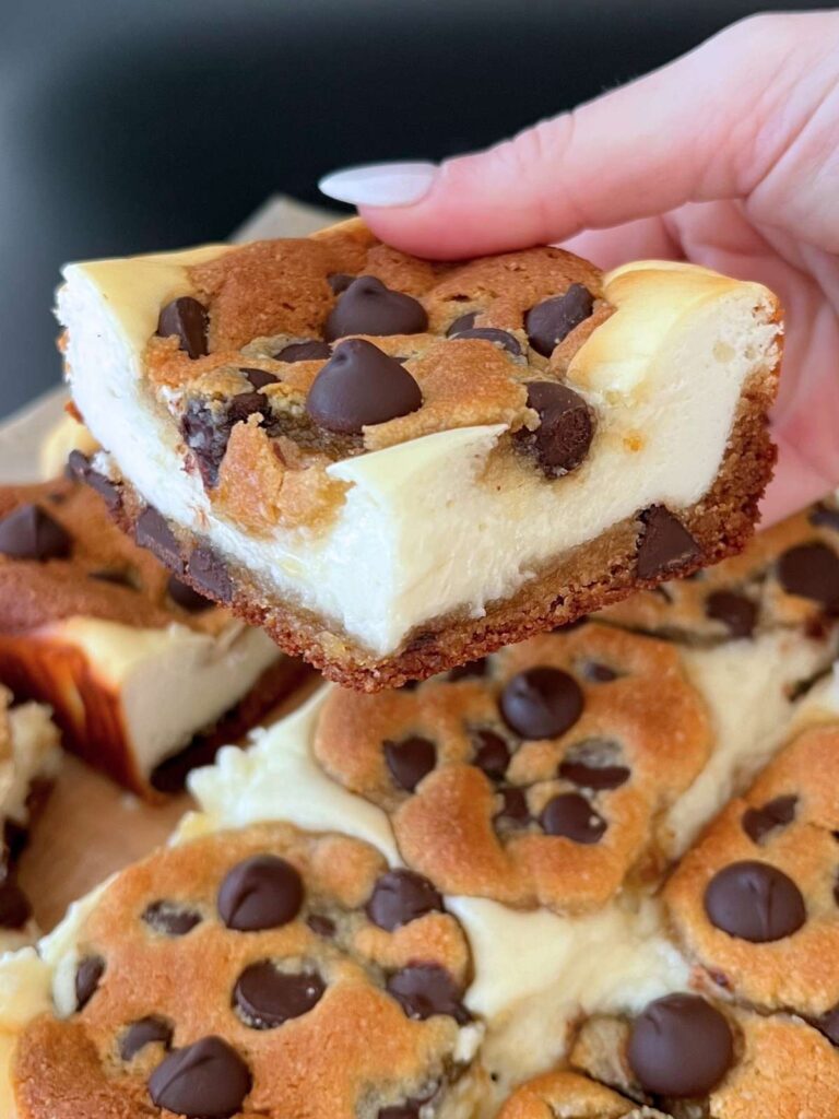 a hand holding a keto chocolate chip cheesecake bar