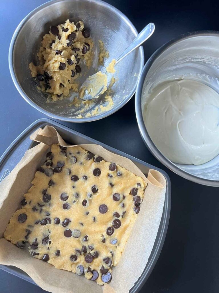 the process of making the bars with cookie dough and cheesecake mixture