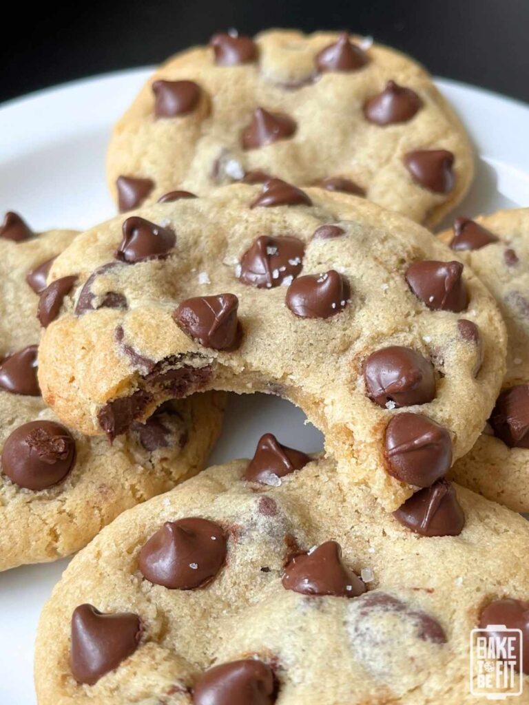 a cookie with a bite taken out of it resting on top of more cookies