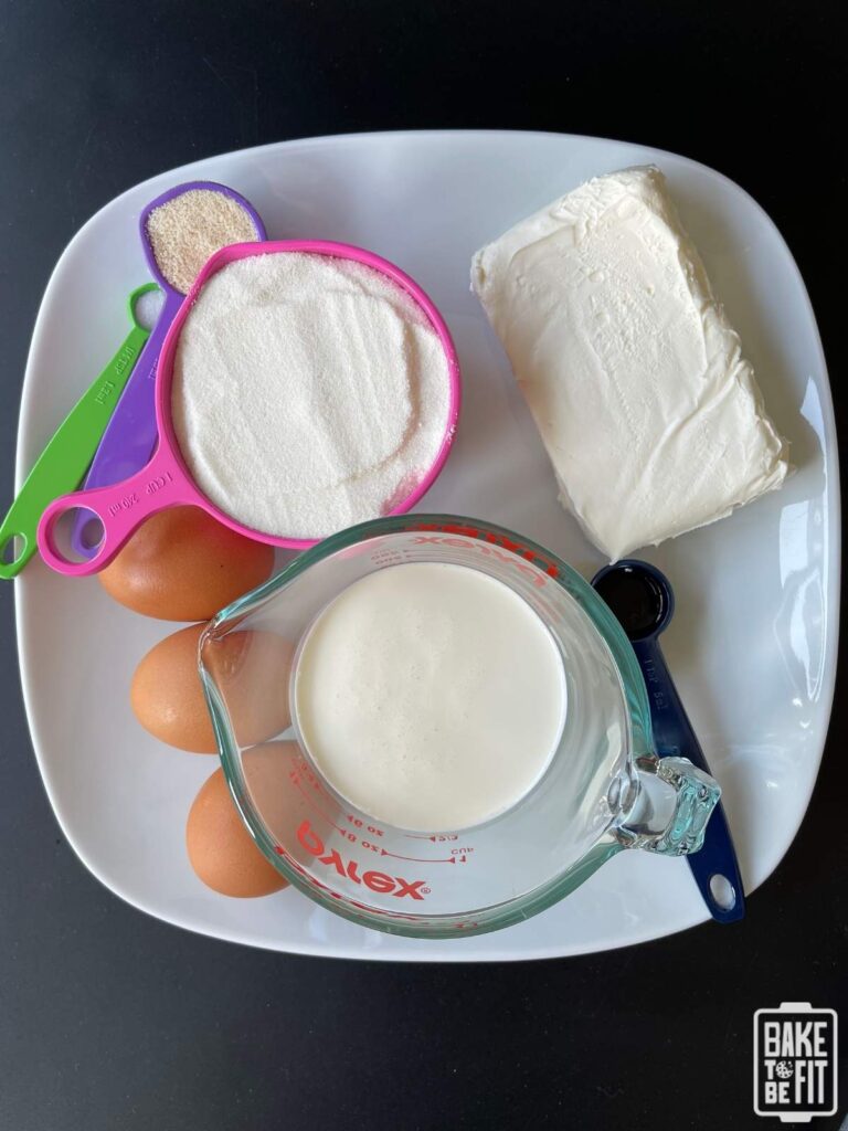 the ingredients to make keto basque cheesecake - heavy cream, eggs, cream cheese, allulose, almond flour, salt, vanilla