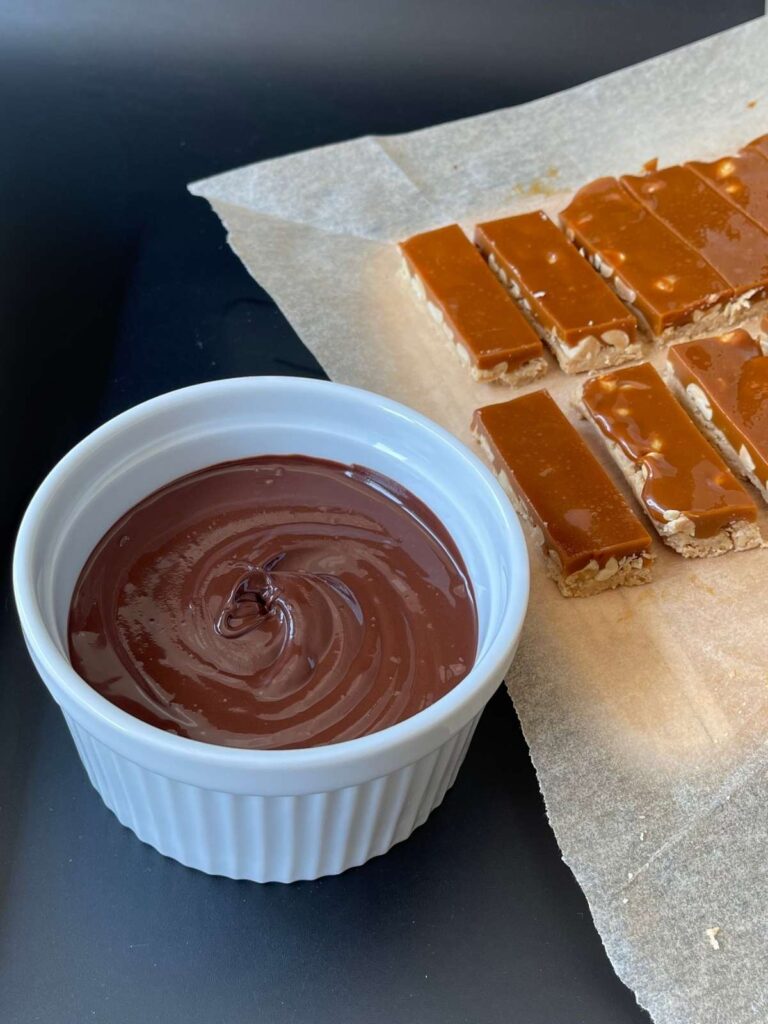 bowl of melted chocolate and snickers bars waiting to be dipped