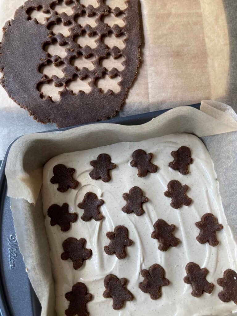 cutting out and arranging the gingerbread cutouts on the cheesecake layer