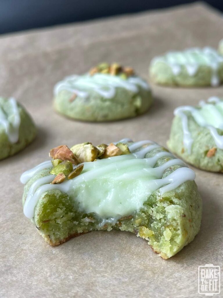 keto pistachio thumbprint cookies on a baking sheet with a bite taken out