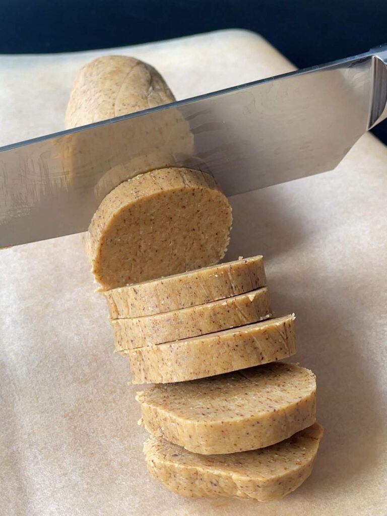 cookie dough log being sliced with a knife